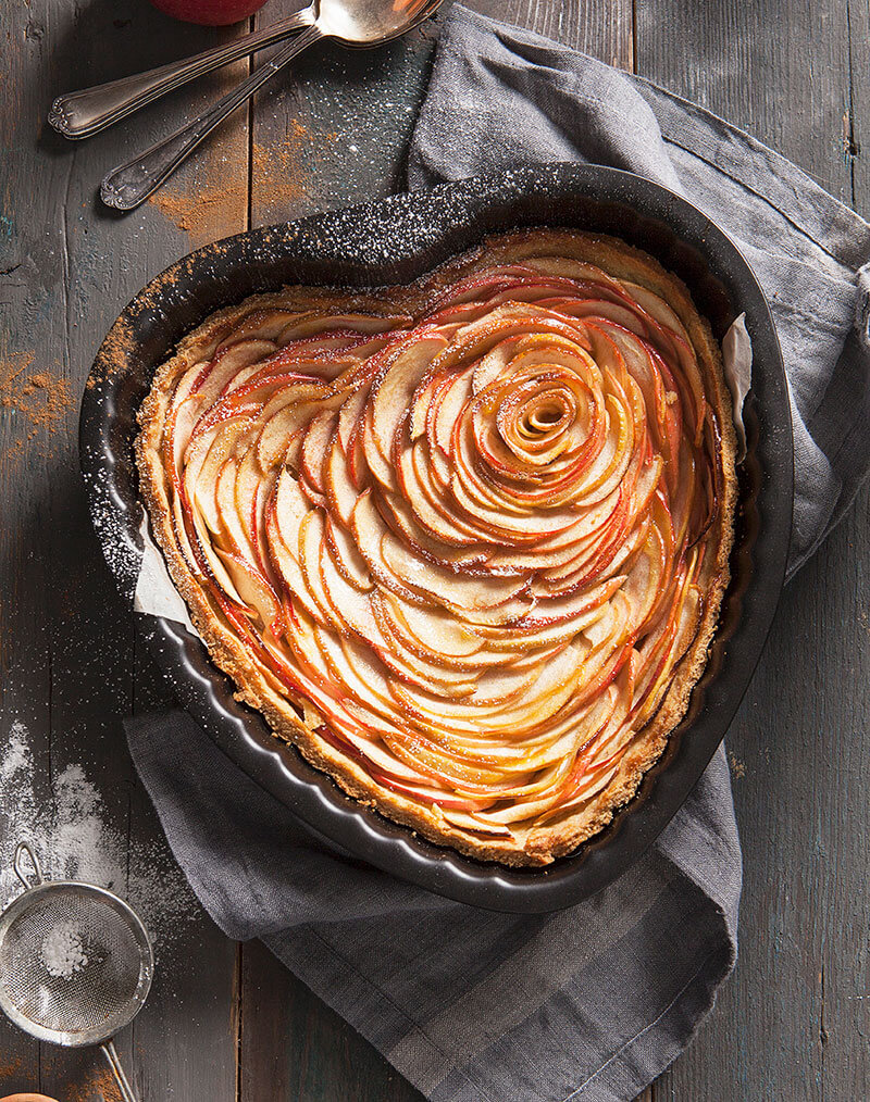 A heart-shaped apple tart with a dusting of icing sugar and cinnamon