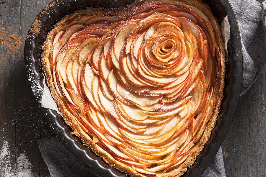 A heart-shaped apple tart with a dusting of icing sugar and cinnamon