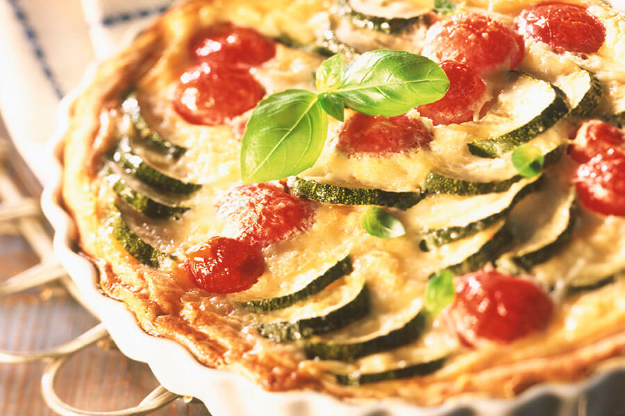Courgette and tomato quiche garnished with basil